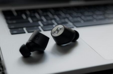 Comparing AirPods Pro 3 vs Sony WF-1000XM5 for Commuters Wireless earbuds on wooden surface showing modern audio technology design
