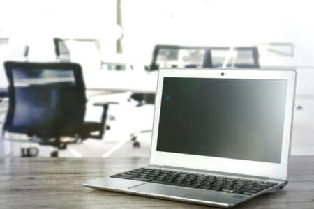 Person working at computer in modern office environment with multiple screens displaying productivity software