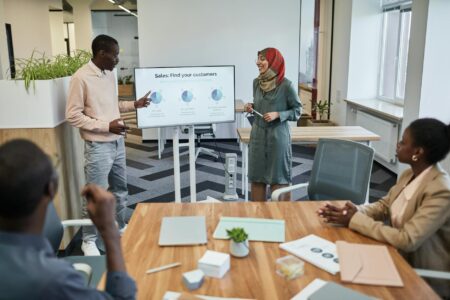 Why Portable Projectors Are Becoming Essential for Remote Presentations Professional presenting to colleagues in modern conference room with projection screen