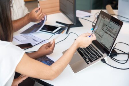 Business professionals reviewing AI software spending data on laptops in a modern office