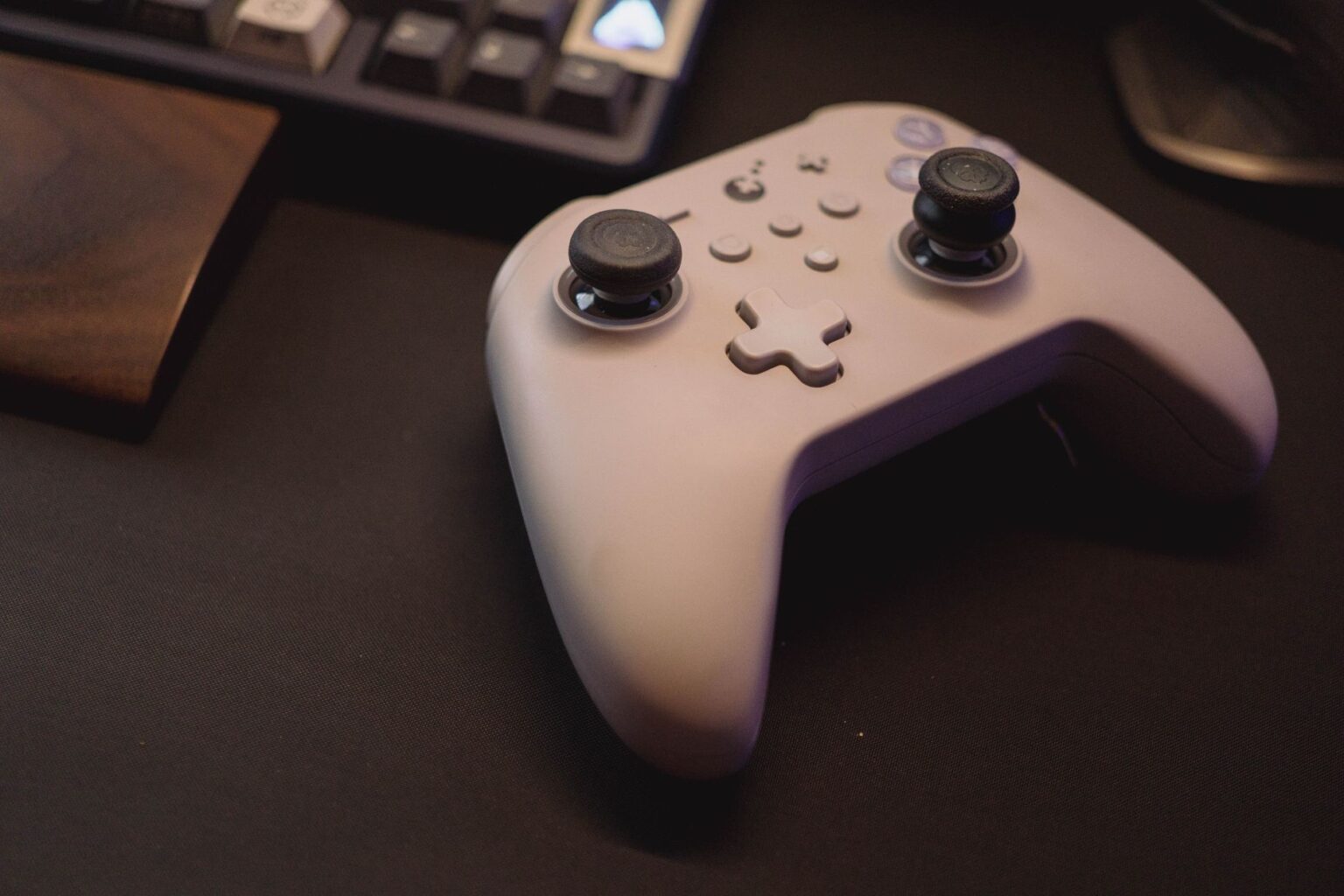 A gaming controller resting on a desk next to a PC setup