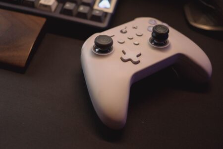 A gaming controller resting on a desk next to a PC setup