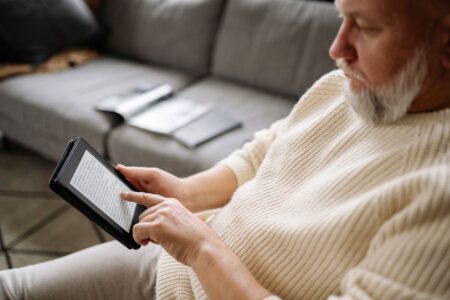 Person holding an e-reader device while reading indoors