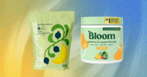A scoop of green superfood powder next to a glass of water on a kitchen counter