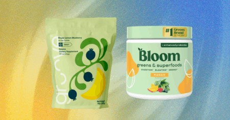 A scoop of green superfood powder next to a glass of water on a kitchen counter