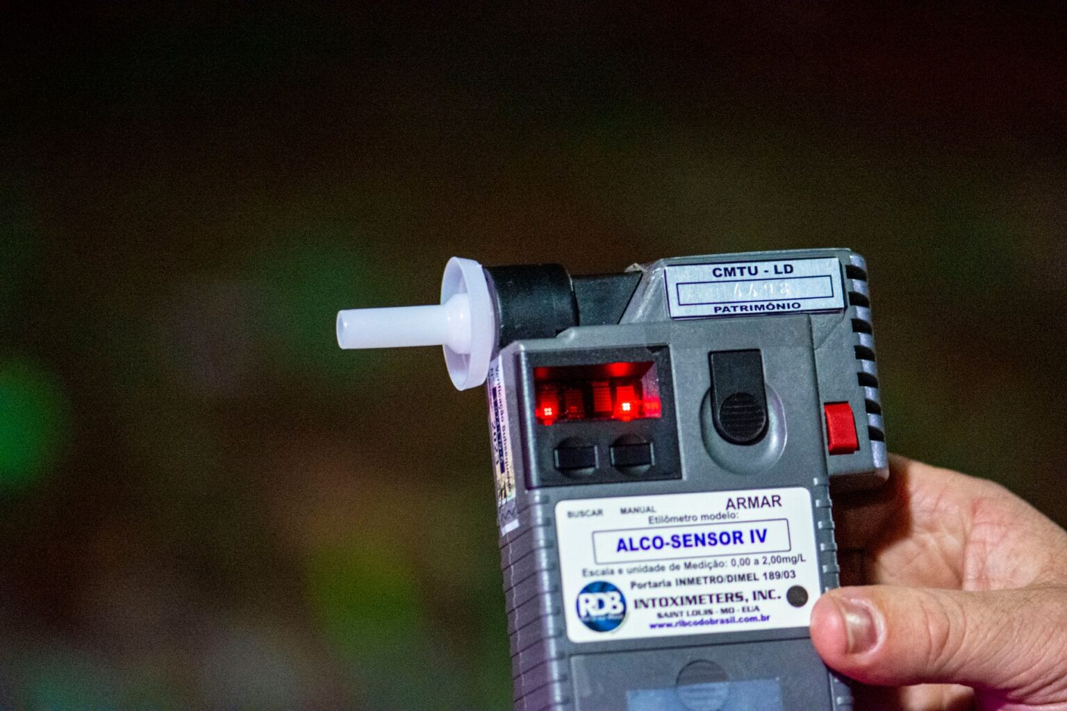 Person exhaling into a small handheld breathalyzer device for health monitoring