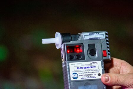 Person exhaling into a small handheld breathalyzer device for health monitoring