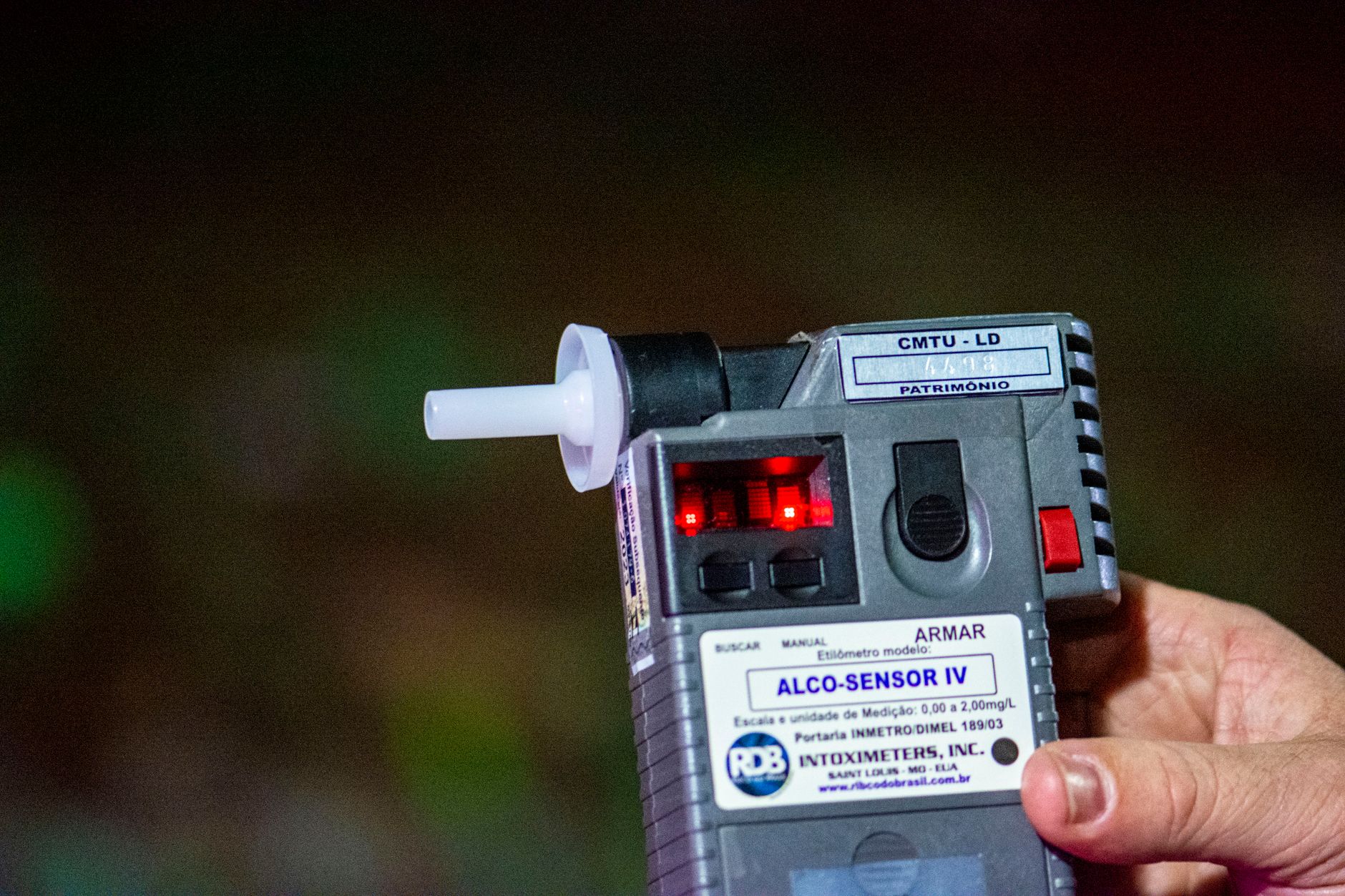Person exhaling into a small handheld breathalyzer device for health monitoring