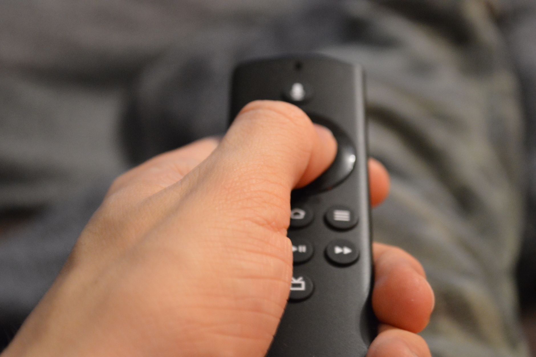 Person sitting on a couch with a remote control watching a streaming service