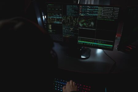 A dark computer screen displaying cybersecurity threat data and code