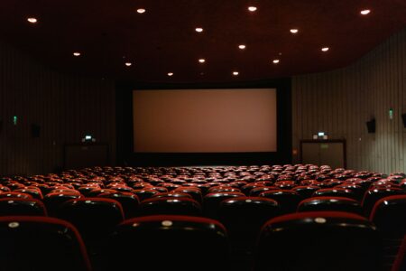 Large movie theater screen viewed from audience seating in a dark auditorium
