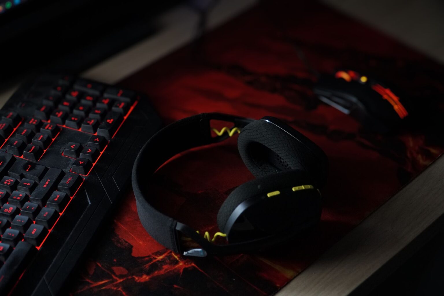 A pair of stereo headphones resting on a gaming desk setup