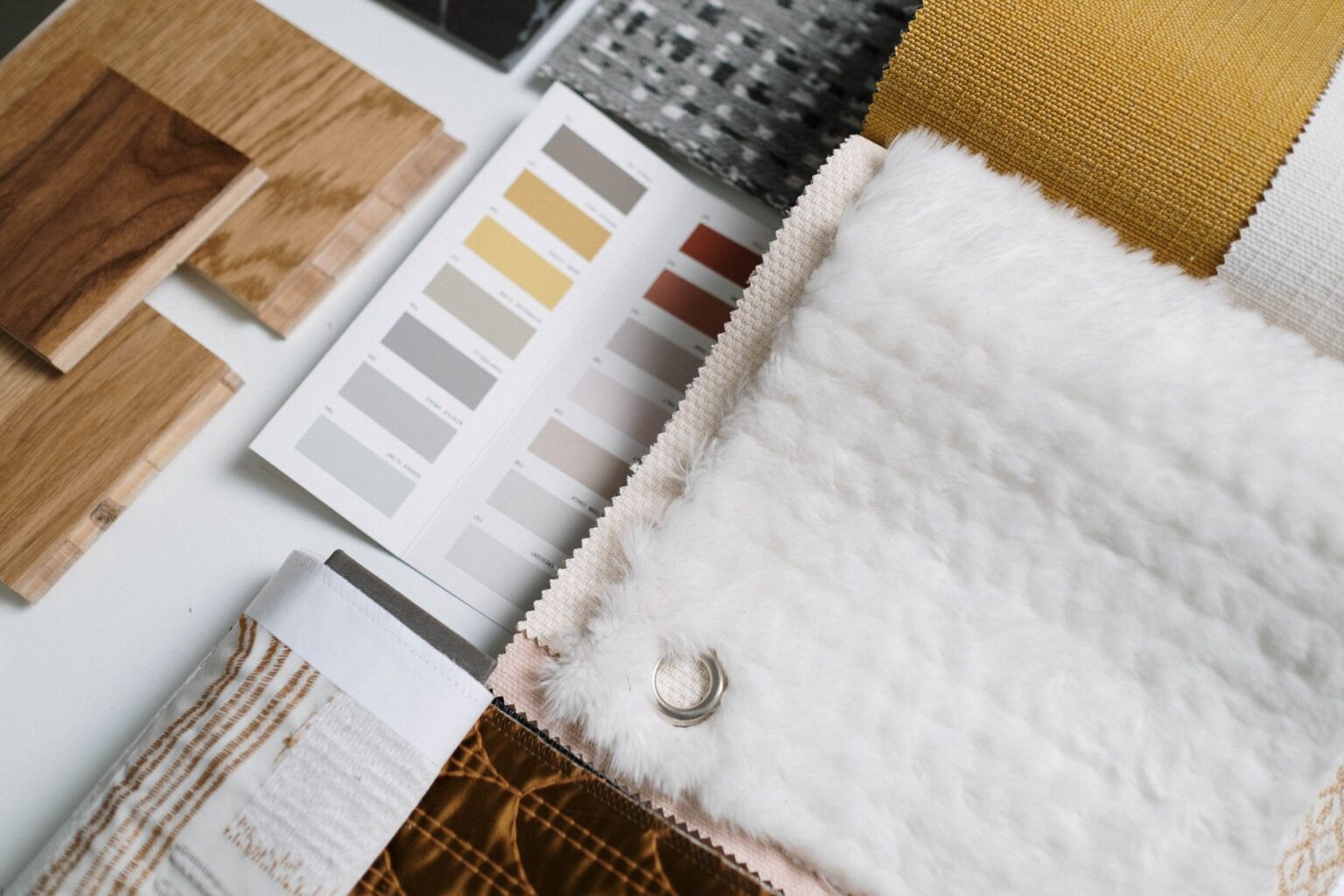 A mood board with home decor swatches and room inspiration photos spread on a table