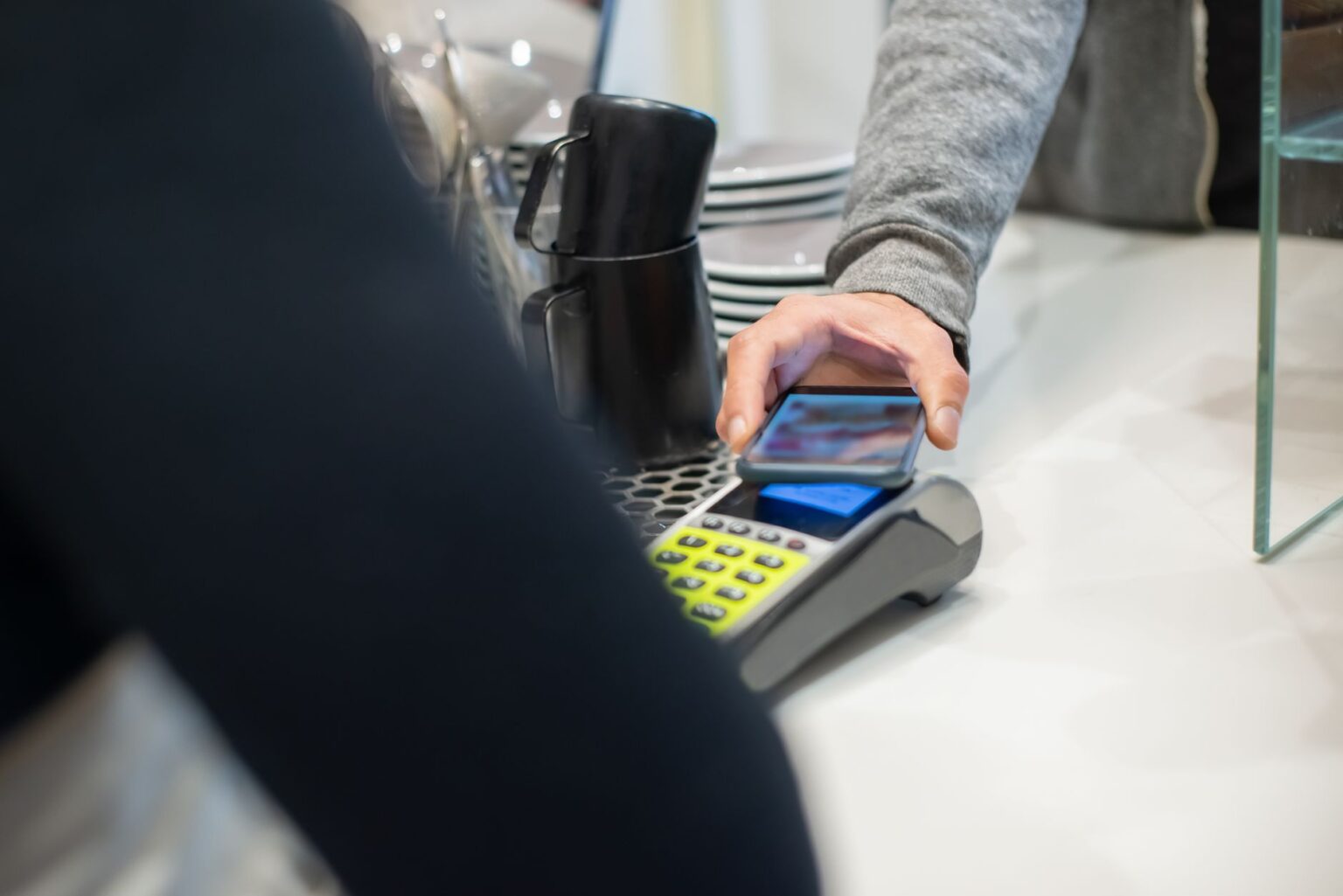 Google Wallet vs. Samsung Wallet: Where Each One Pulls Ahead Person holding a smartphone near a contactless payment terminal