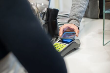 Person holding a smartphone near a contactless payment terminal