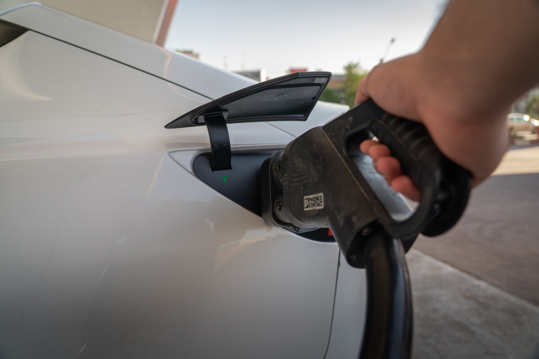 A luxury electric vehicle connected to a charging station in an urban setting